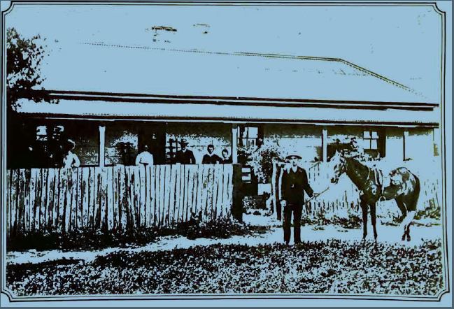 black and white photo of an old building with people gathered outside