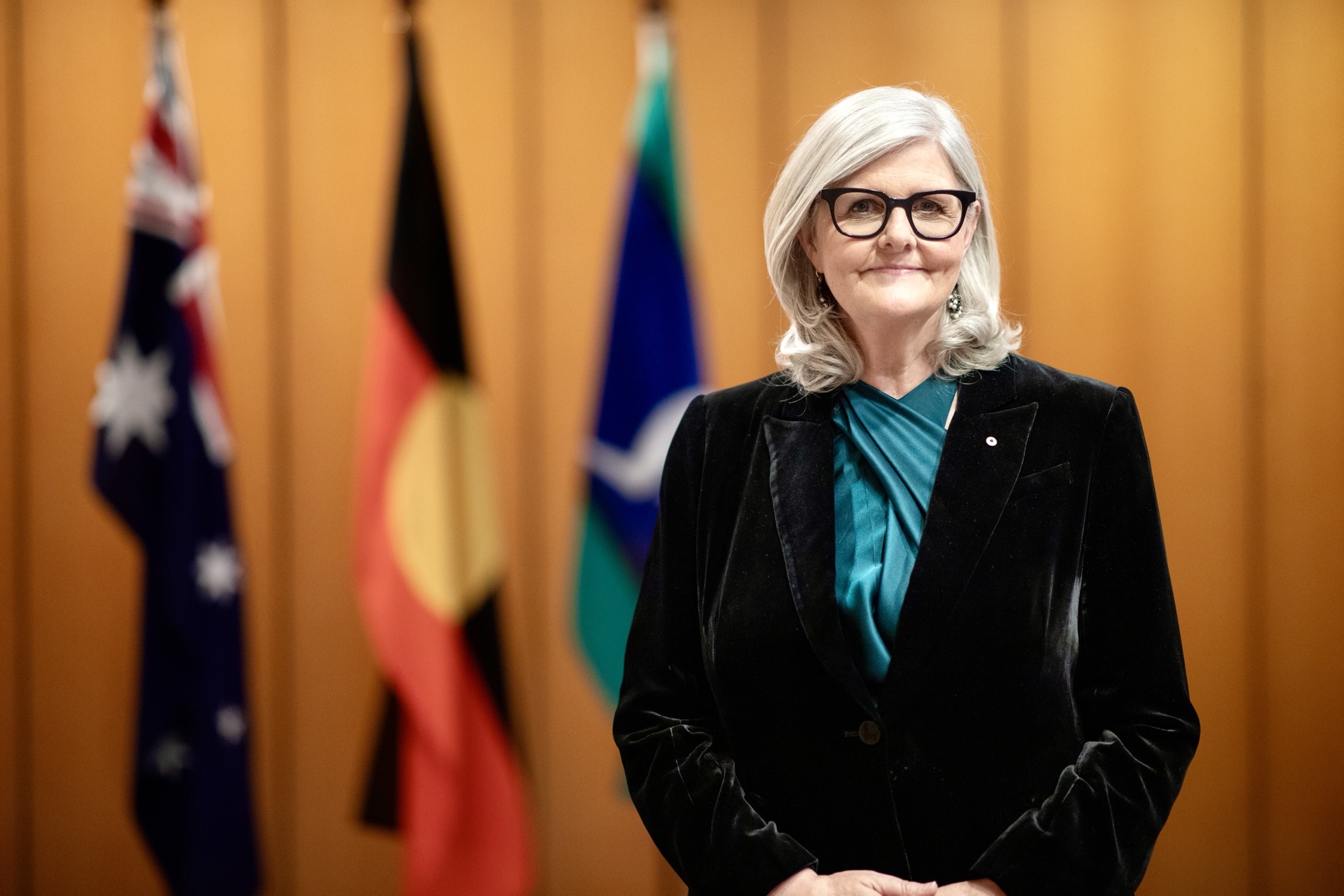 the Governor-General standing in front of the Australian national flag, Aboriginal flag, and Torres Strait Islander flag