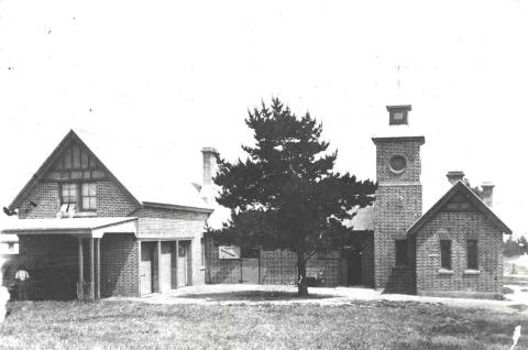 a black and white photo of a building with a tree in the foreground